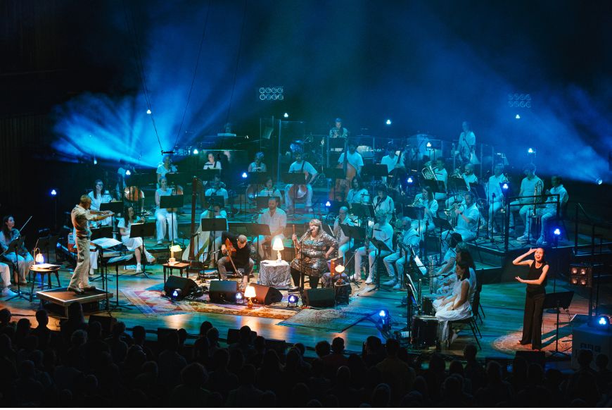 an orchestra on a stage, lit by blue lights